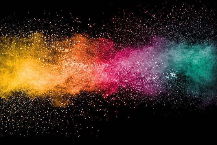 Close-up of powder paint splattering against black background