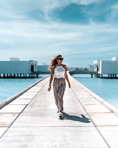 Full length of woman standing on pier against sky