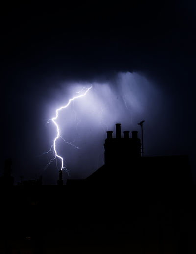 Lightning over silhouette of building at night