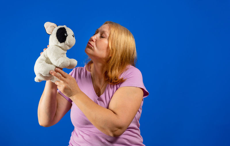 Woman holding toy against blue background
