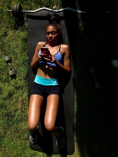 Young woman using phone while lying on grass