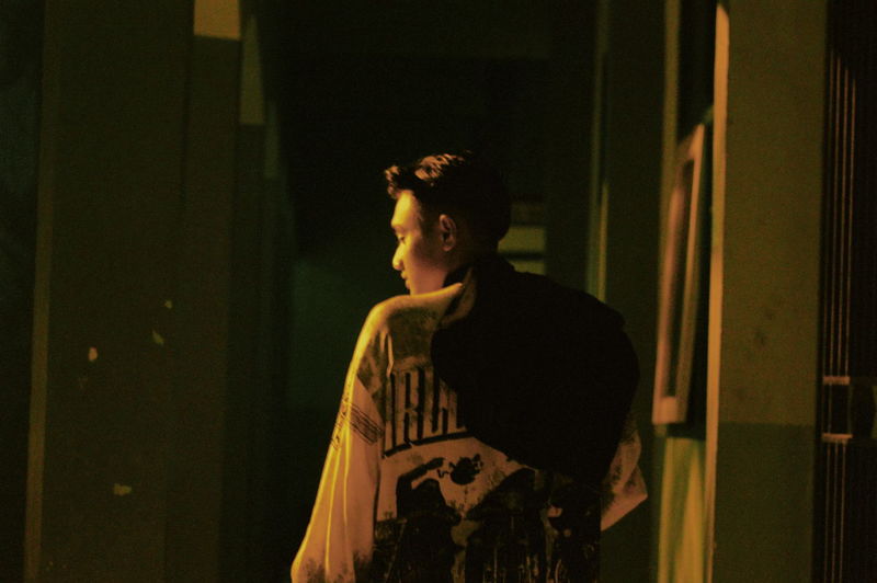 Rear view of young man walking in dark building