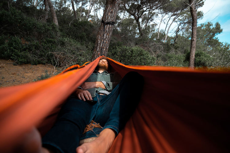 Full length of man sleeping in hammock in forest