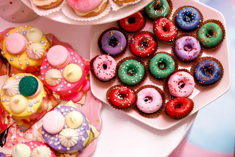 Colorful donuts and cakes, decorated with pastry beads, meringue and macarons, on the table