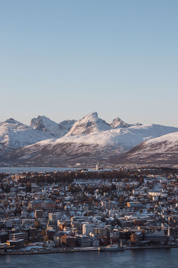 View of the polar town of tromso in northern norway and the snowy hills in background at sunset. 