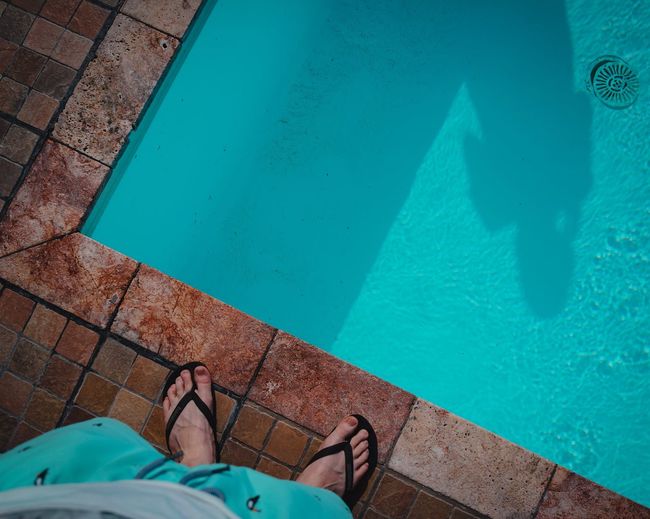 Low section of man standing by swimming pool