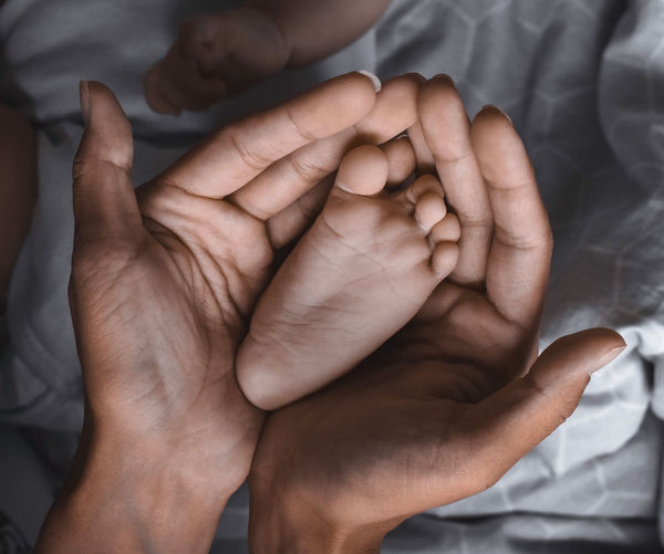 Cropped hands of mother holding baby foot