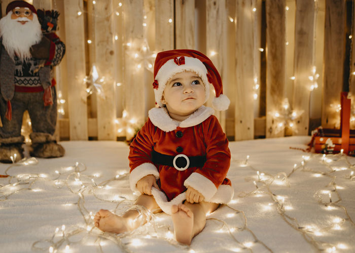 A little girl sitting in a santa claus outfit.