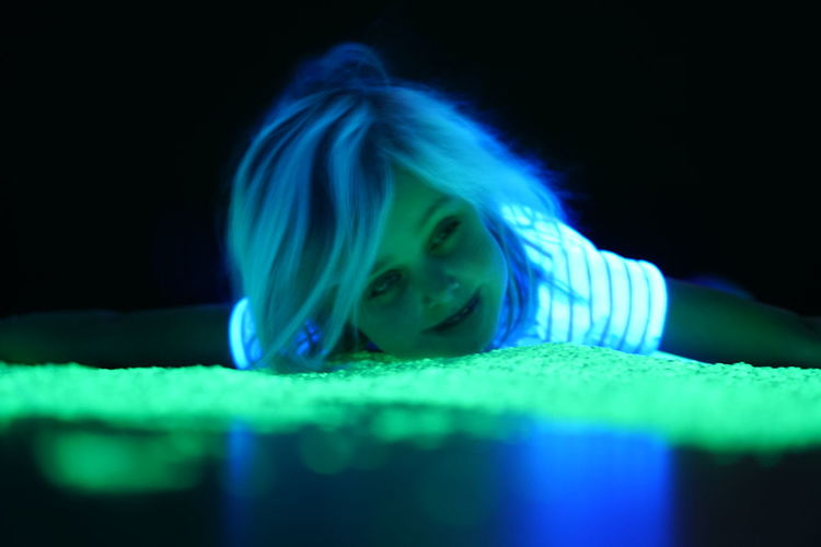 Portrait of woman looking at illuminated nightclub