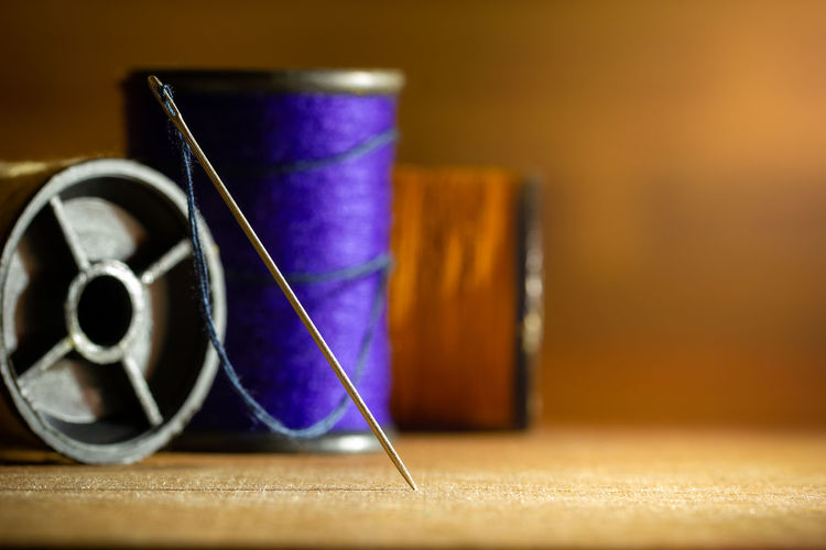 Close-up of spool and needle on table