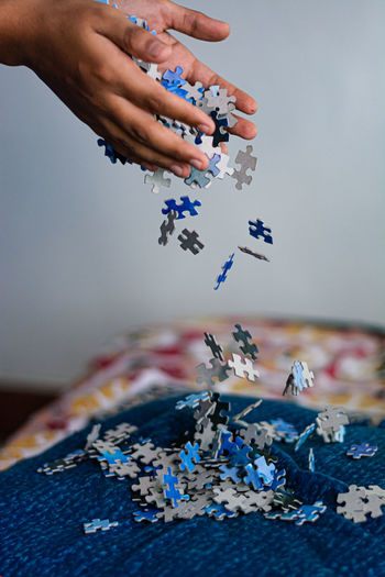 Cropped hands throwing jigsaw pieces on bed