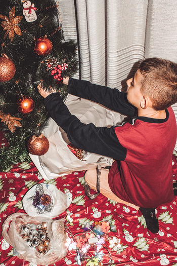 Rear view of boy in christmas tree at home