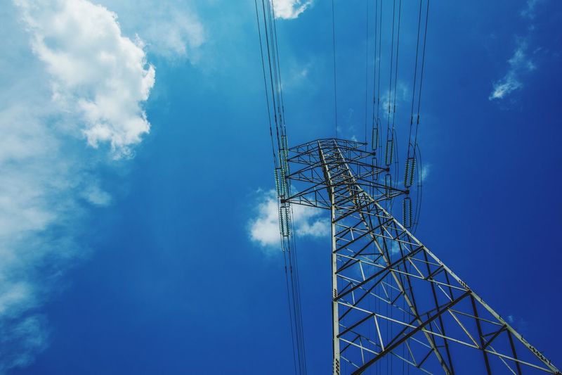 Low angle view of electricity pylon against blue sky