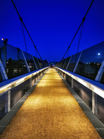 Illuminated bridge against clear blue sky at night