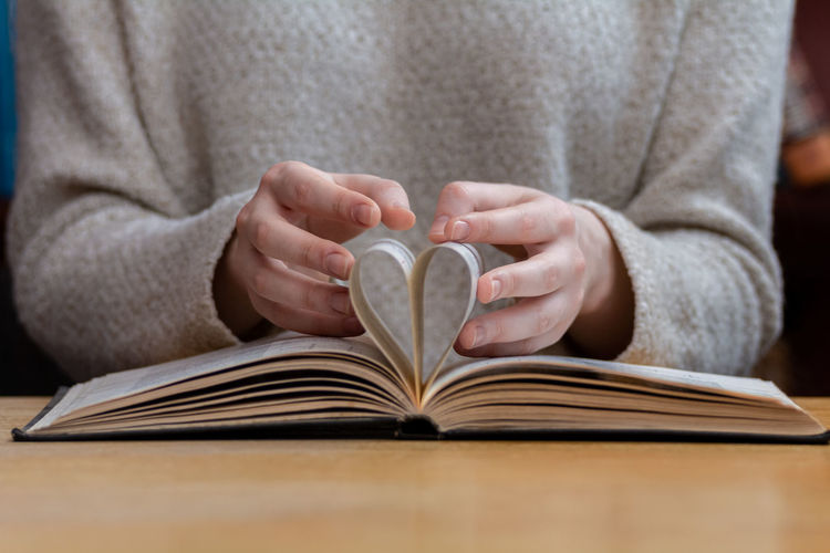 Woman folded the pages of the book in the shape of a heart