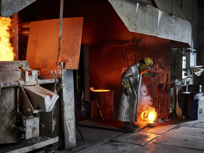 Craftsperson pouring burning metal while working in industry