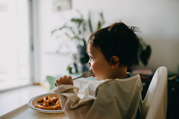 Boy looking away while sitting on table