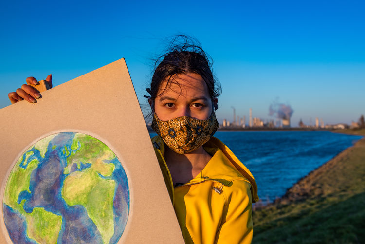 Portrait of woman wearing mask holding earth painting