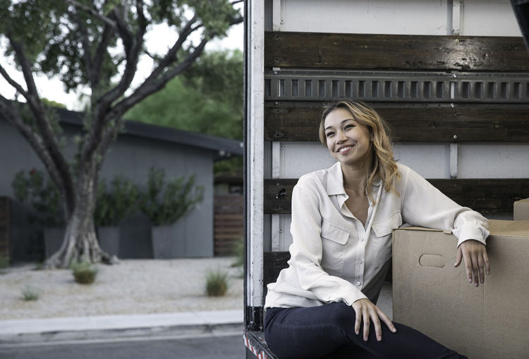 Woman sitting inside moving truck with boxes