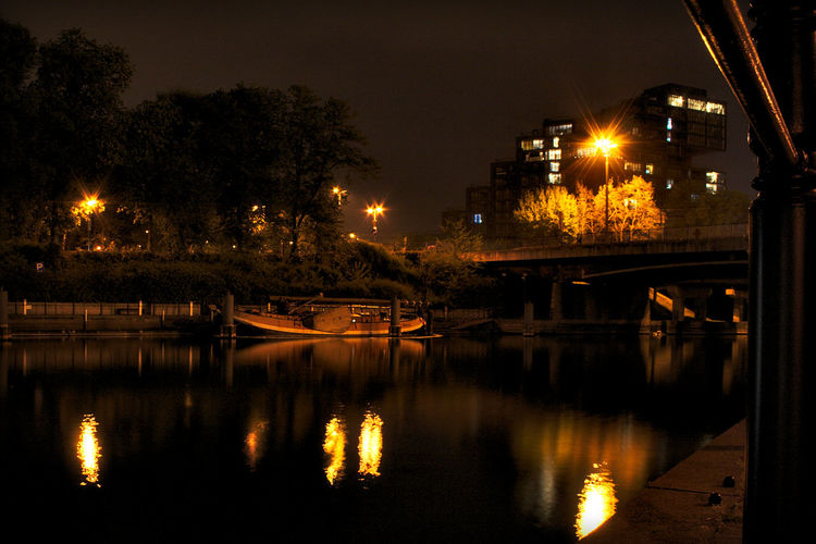 Illuminated street lights by river at night