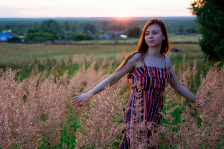 Young woman standing amidst plants on land
