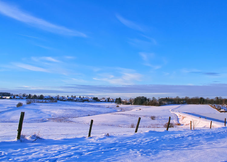 Snow covered field against blue sky
