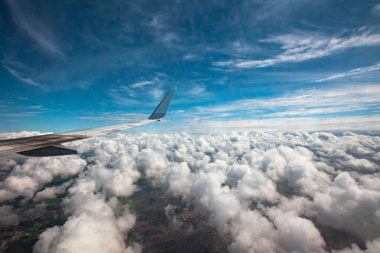 Airplane flying over cloudscape against blue sky