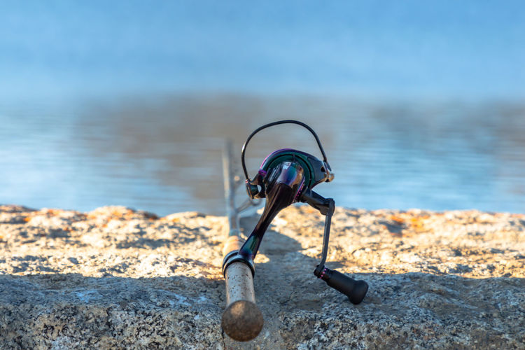 Fishing reel on top of a wall with out of focus water