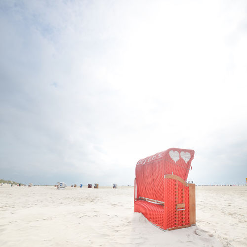 Hooded beach chair on shore against sky