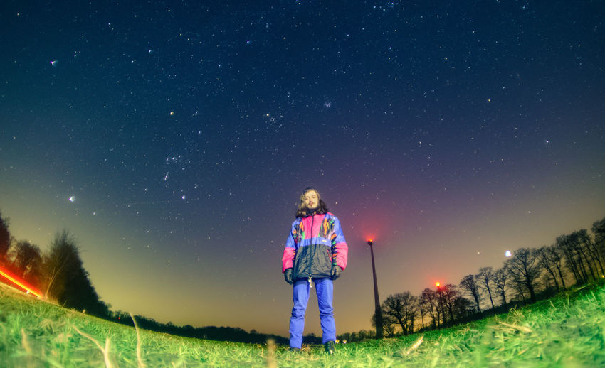 Woman standing on field against clear sky at night