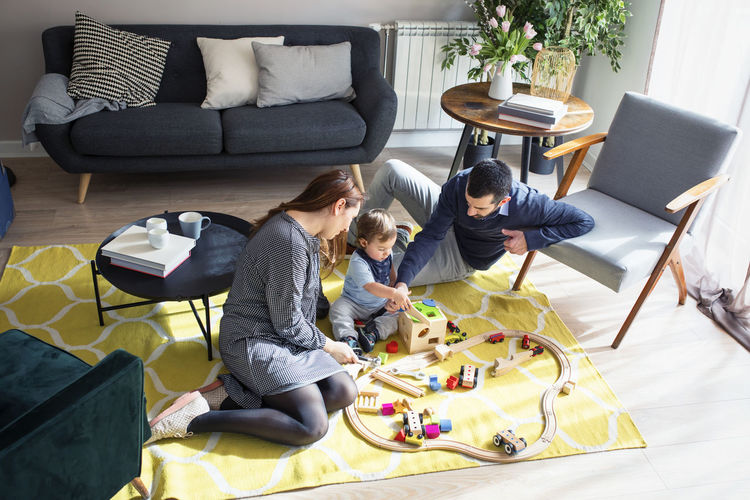 High angle view of parents looking at son playing with toy train at home
