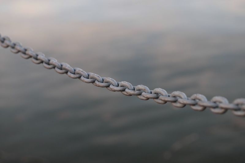Close-up of chain against water