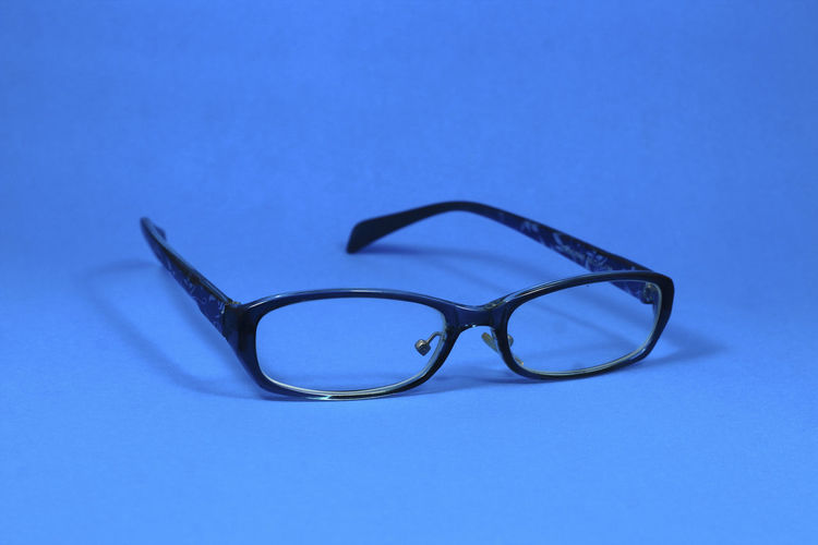 Close-up of eyeglasses on table against blue background