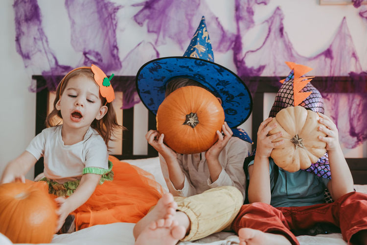 Three little kids in festive halloween costumes with pumpkins having fun. family spending time 