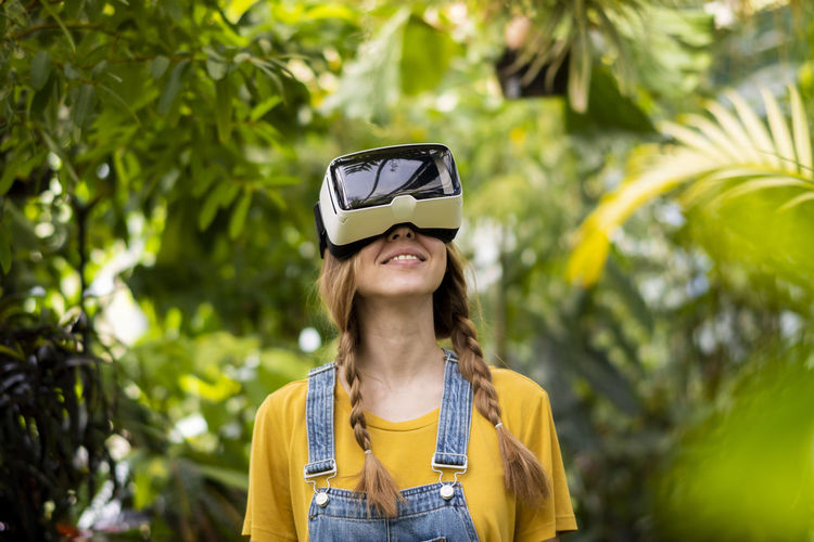 Smiling woman wearing virtual reality simulator standing in garden