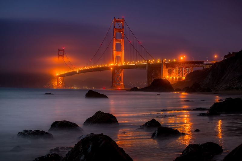 View of illuminated golden gate bridge over sea against sky at dusk