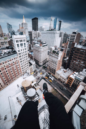 Low section of man and cityscape against sky