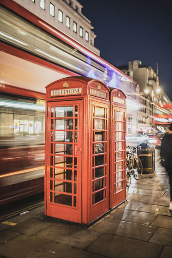 Telephone booth on footpath in city at night