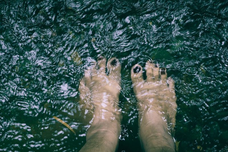 Low section of woman standing in river