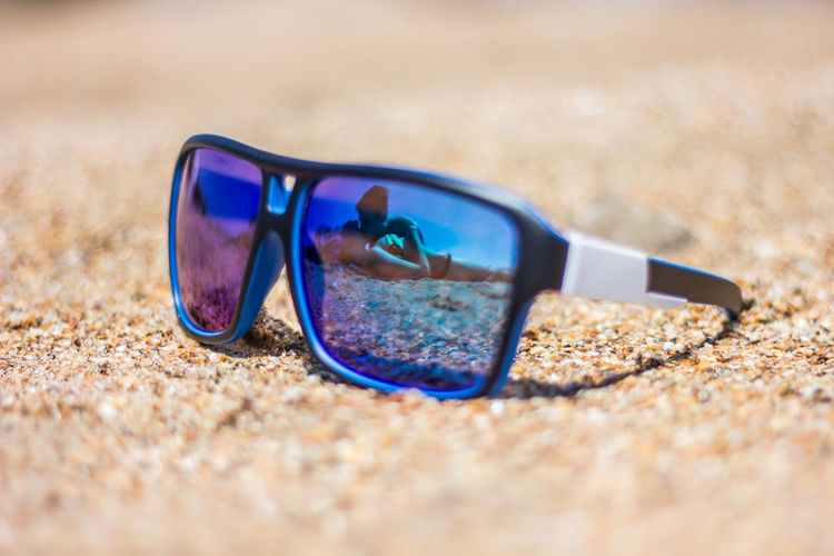 Reflection of couple at beach seen on sunglasses during sunny day