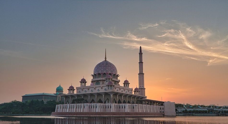 Low angle view of mosque building against sky during sunrise. 