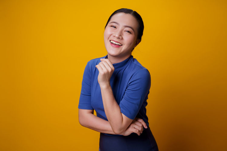 Smiling young woman against yellow background