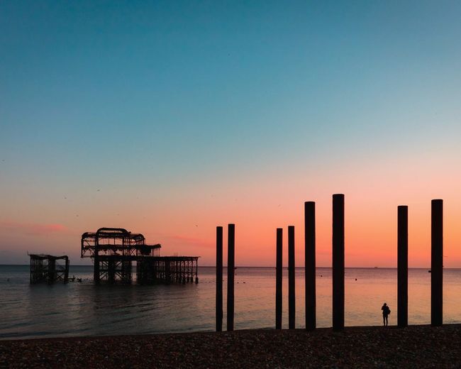 Pier on sea against clear sky during sunset