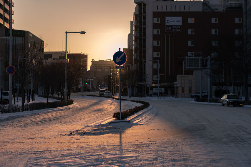 Road by buildings in city during winter
