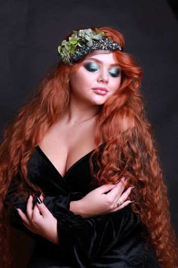 Sensuous young woman wearing wreath against black background