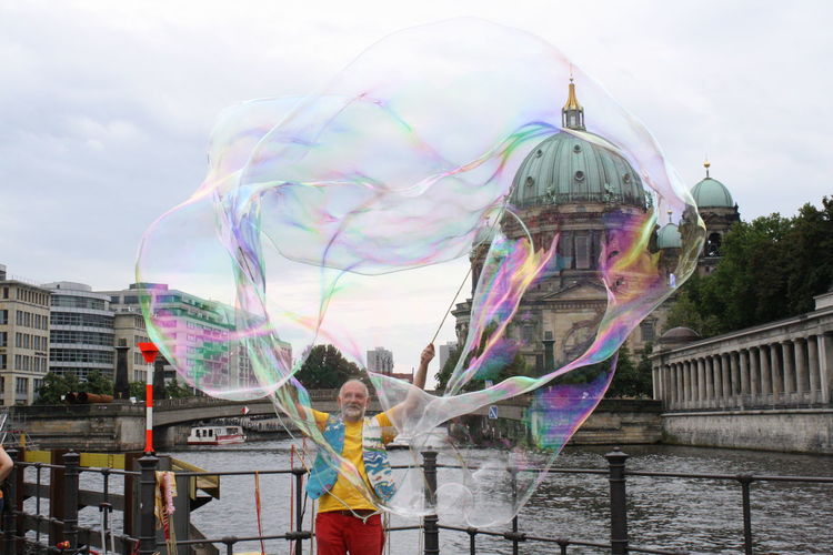 Man blowing colorful oversize soap bubble