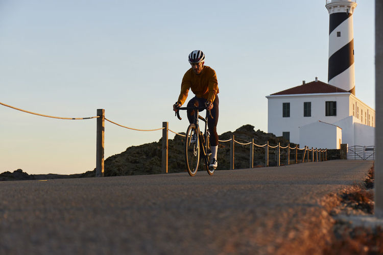 Cyclist riding bicycle in front of lighthouse on road