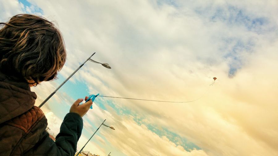 Low angle view of boy flying kite against sky