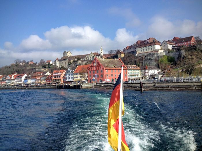 Ship in sea by city buildings against sky