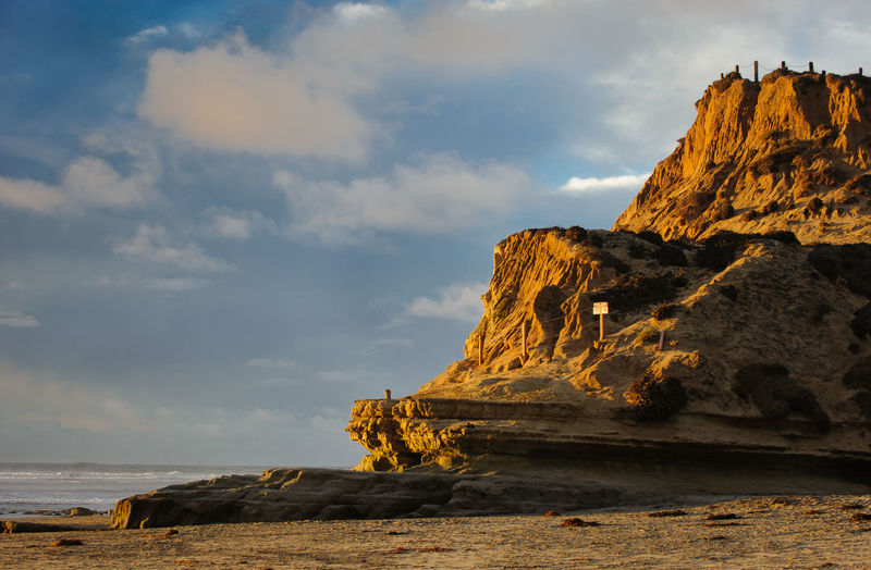 Rock mountain at beach against sky